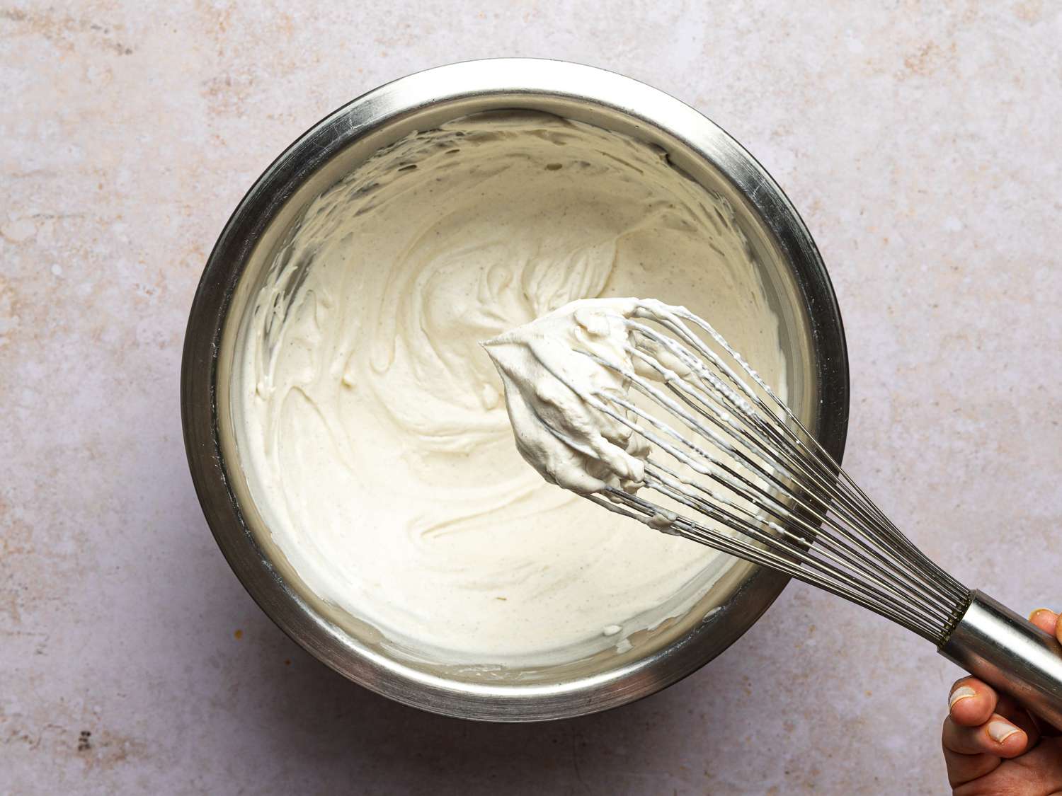 Cream, sour cream, cinnamon, nutmeg, and a pinch of salt beaten until stiff inside a bowl using a wire balloon whisk.