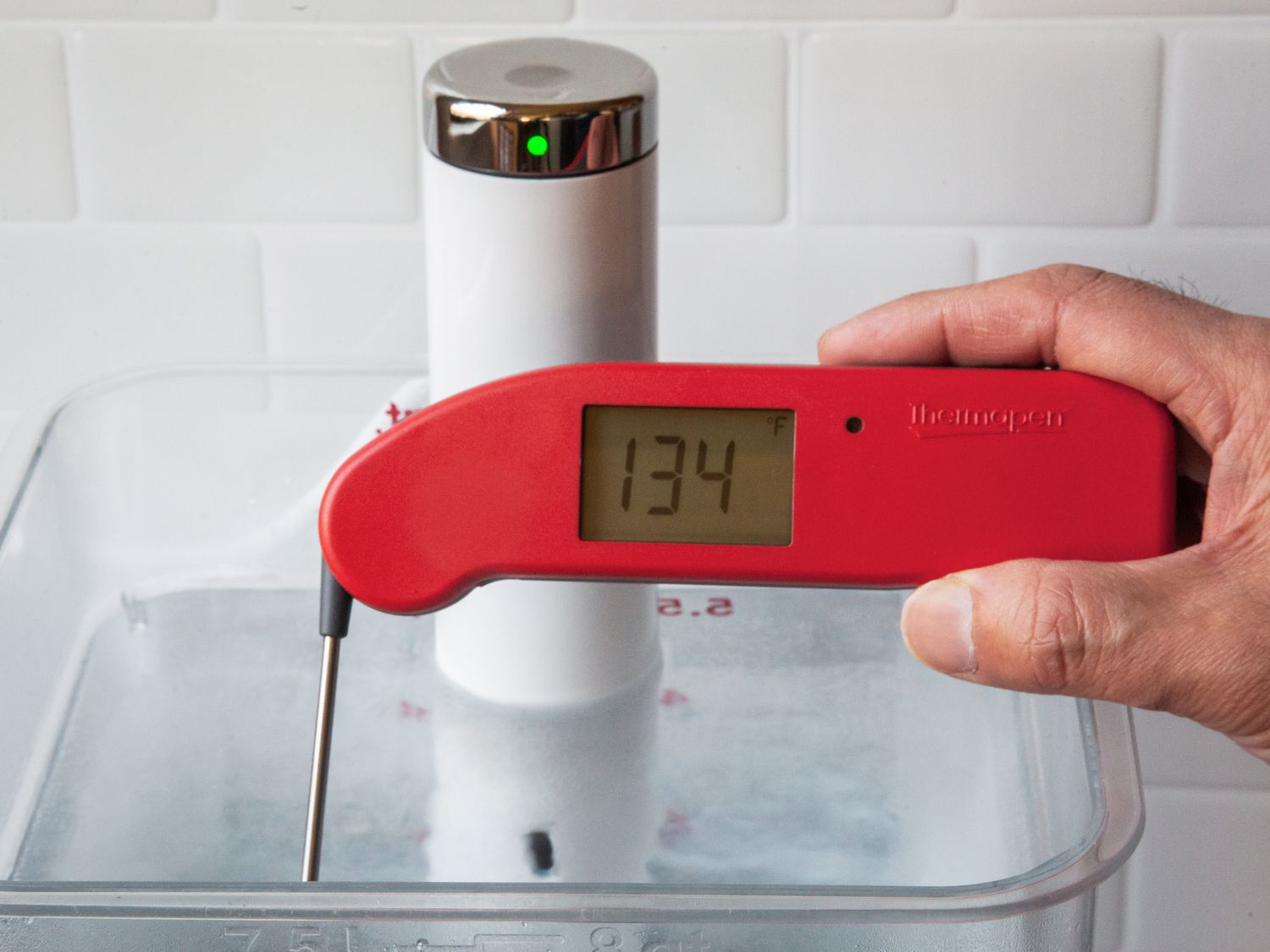 一个Thermapen one taking the temperature of a sous vide water bath set to 134 degrees