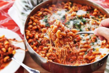 A cheesy skillet of baked pasta with tomato sauce and ground beef