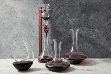 four different styles of wine decanters against a grey background