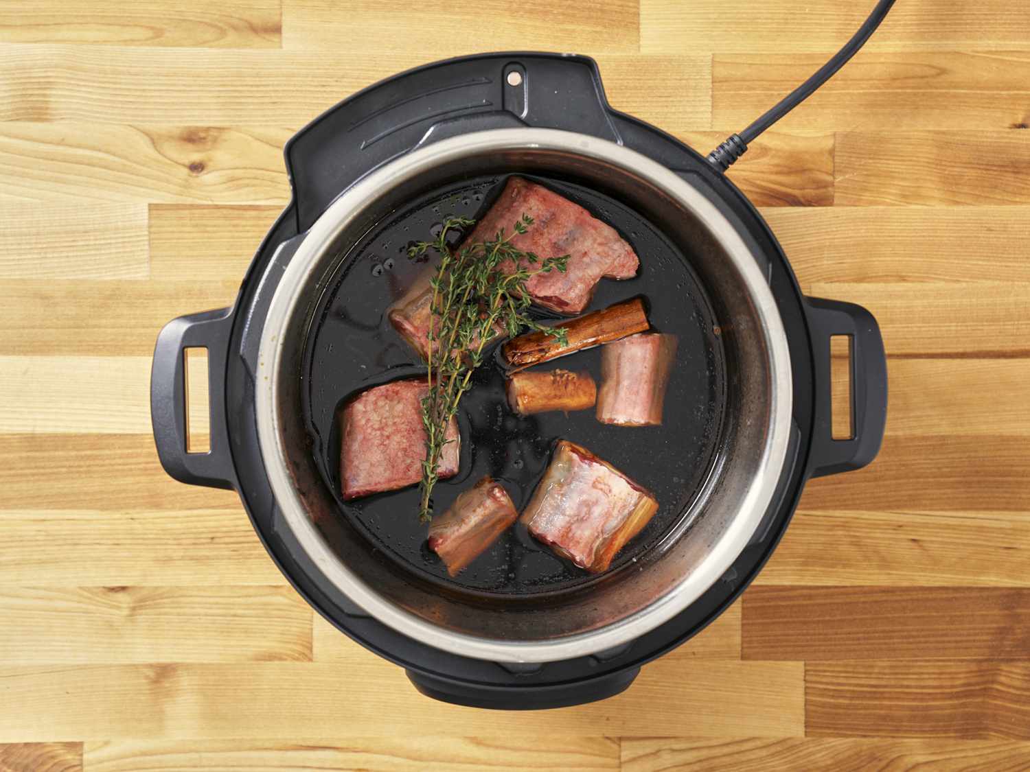 Seasoned oxtail in a pressure cooker.