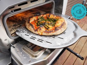 a pizza on a pizza peel coming out of a pizza oven