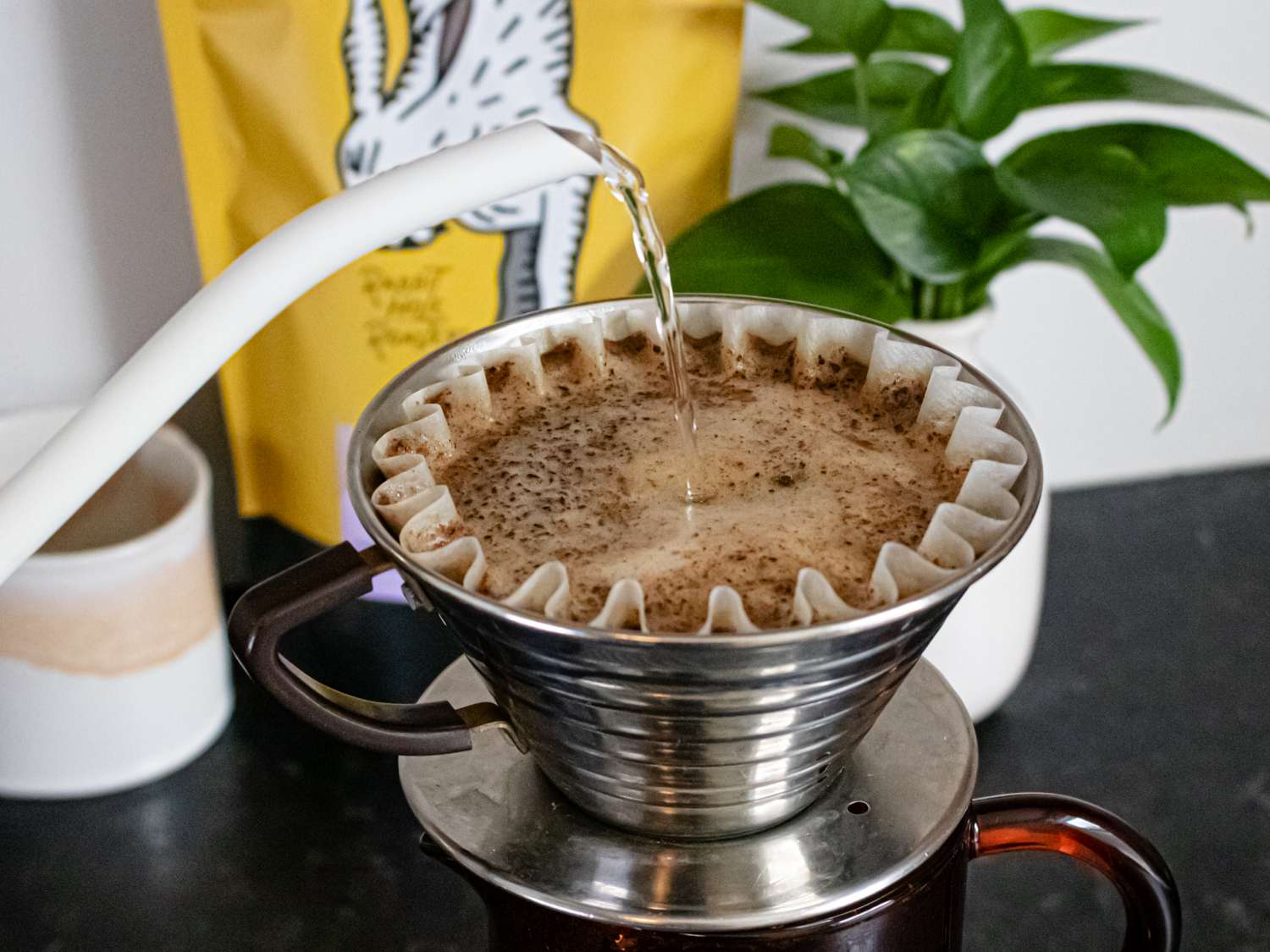 A teapot pouring water into coffee, no bloom