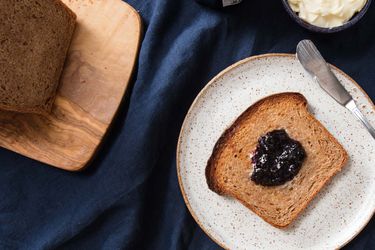 A slice of 100% whole wheat bread, toasted and topped with jam