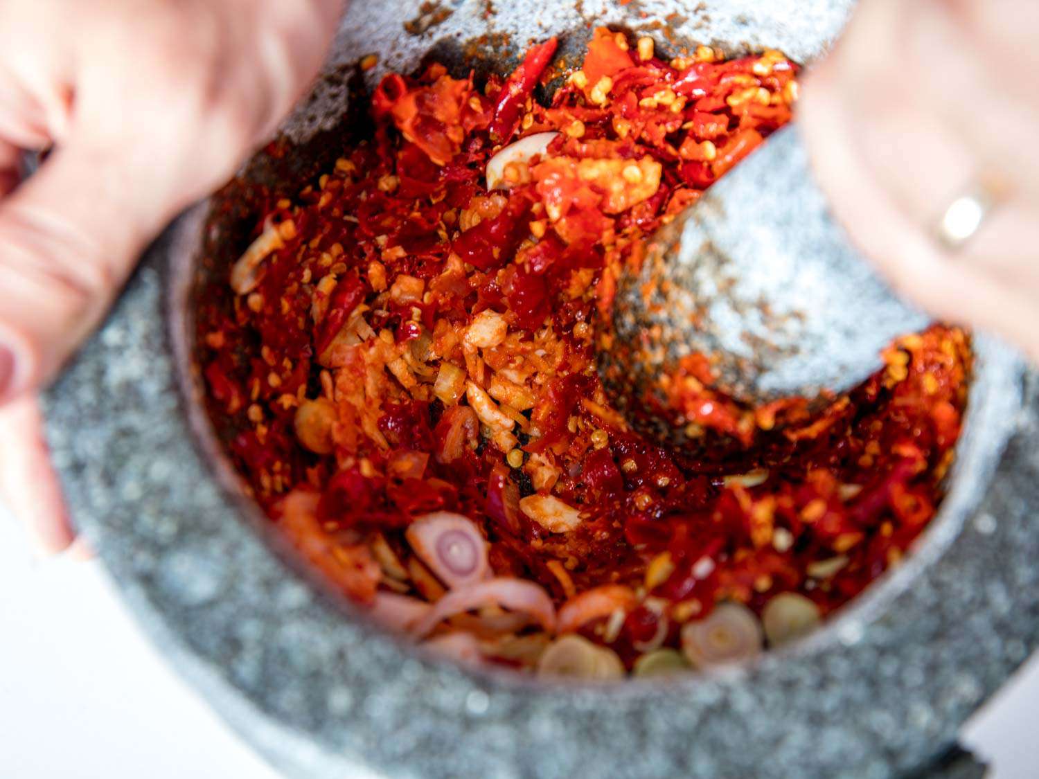 Thai red curry paste ingredients being ground with a mortar and pestle