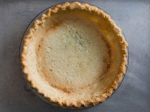 An empty blind-baked pie crust in a glass pie plate.