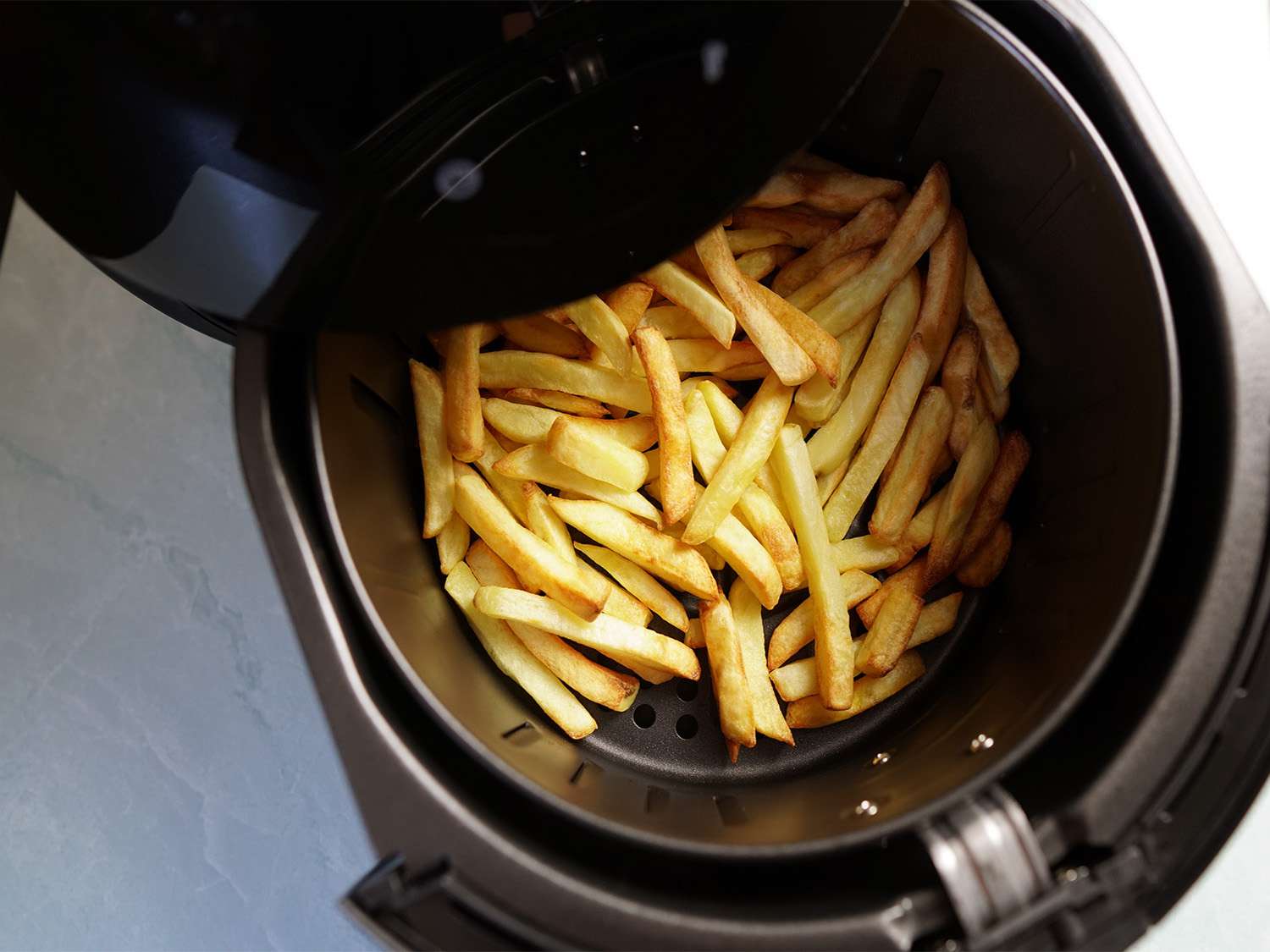 An air fryer basket containing fries