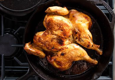 a whole chicken in a cast iron skillet on a stovetop