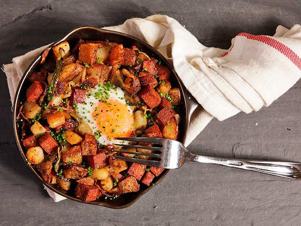 Overhead view of a cast iron skillet full of Spam hash, topped with an over-easy egg.