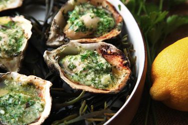 Closeup of grilled oysters topped with Parmesan basil compound butter.