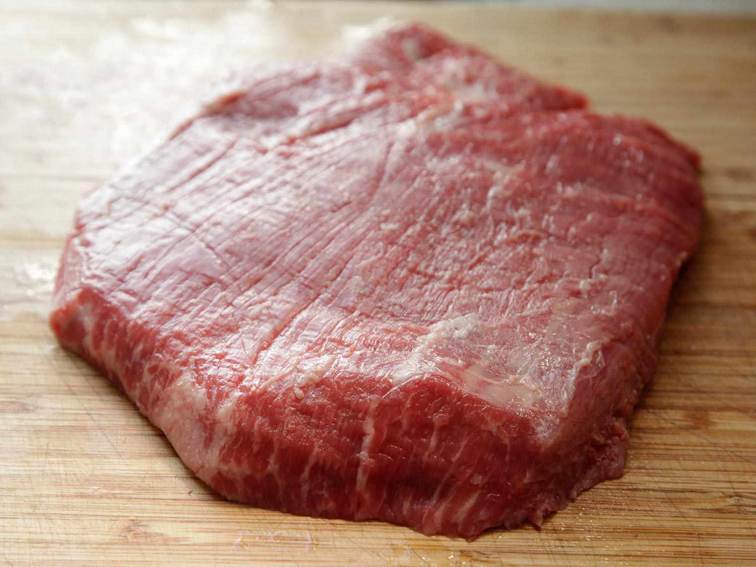 Raw flank steak on a wooden surface