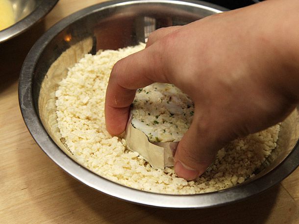 将蟹饼用箔纸包好，包上面包屑，放入钢制搅拌碗中。