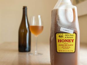 前景是一瓶半加仑的蜂蜜，背景是一瓶和一杯蜂蜜酒。