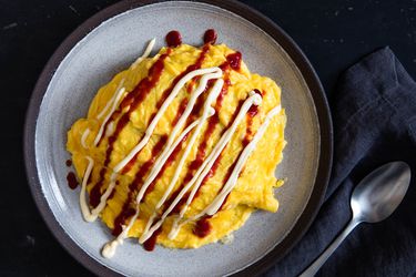 Overhead of homemade chicken omurice drizzled with ketchup and kewpie mayo.