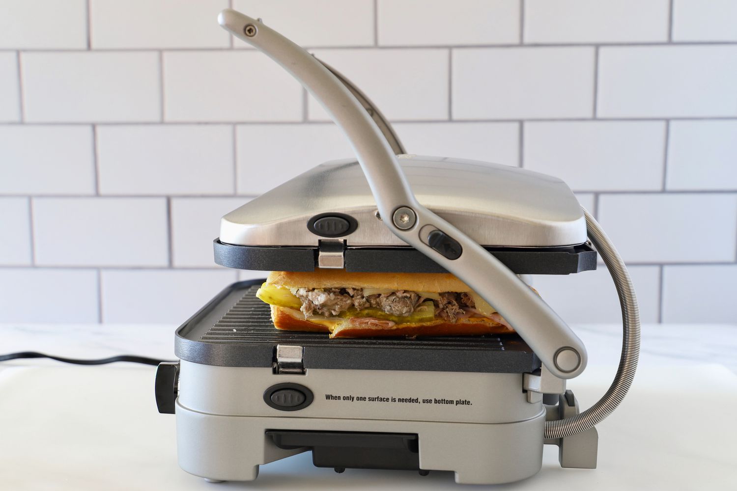 a panini press with its lid closed pressing a cubano