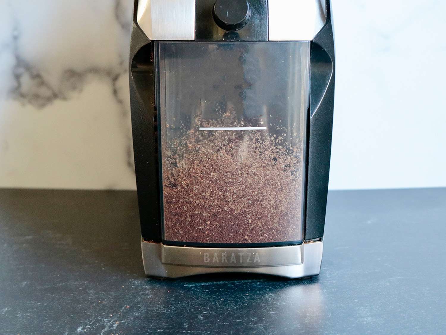 一个咖啡研磨机上的研磨捕捉箱的特写，里面装满了能产生静电的咖啡渣