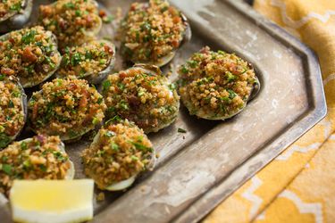 A tray of easy, ultimate Clams Casino with a lemon wedge.