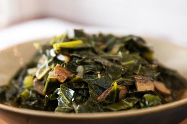 Bowl filled with braised vegan collard greens with chunks of mushrooms