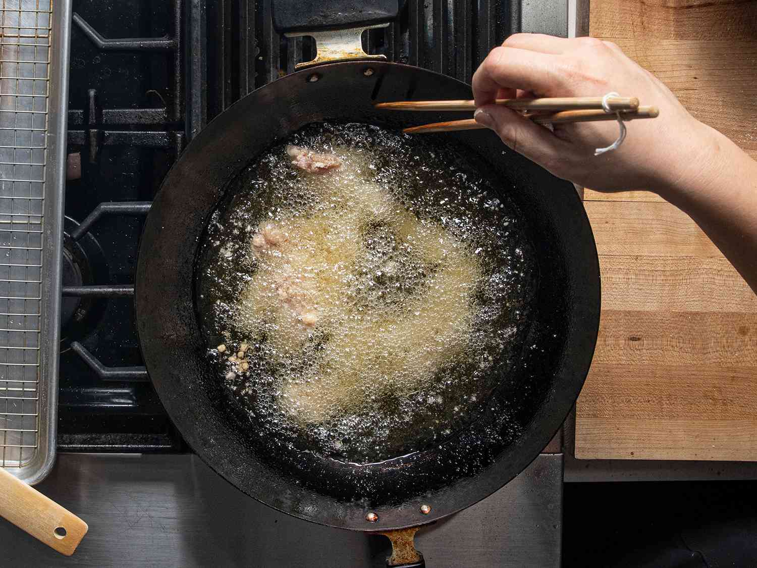 鸟瞰图:鸡在锅里炸，用一双筷子搅拌
