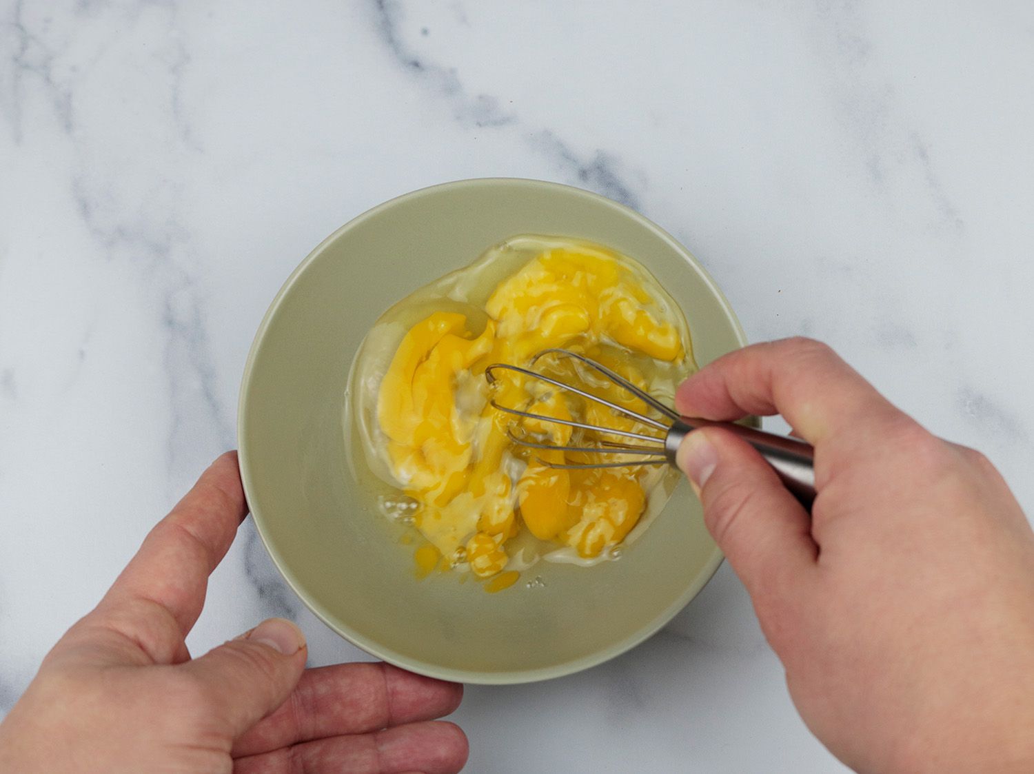 a miniature whisks beats three eggs in a bowl