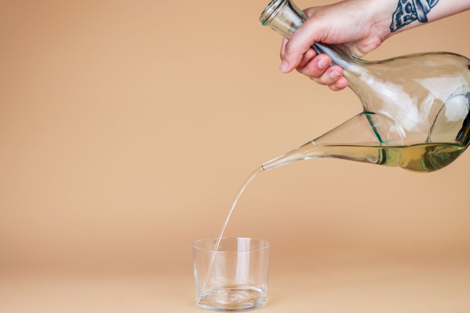 a hand pouring from a porron into a cup