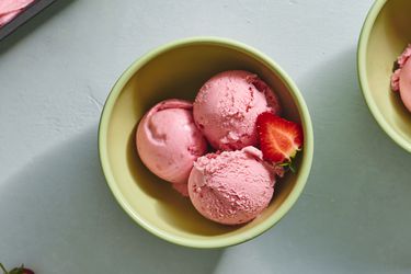 三勺草莓冰淇淋放在陶瓷碗里，外加半个新鲜草莓。