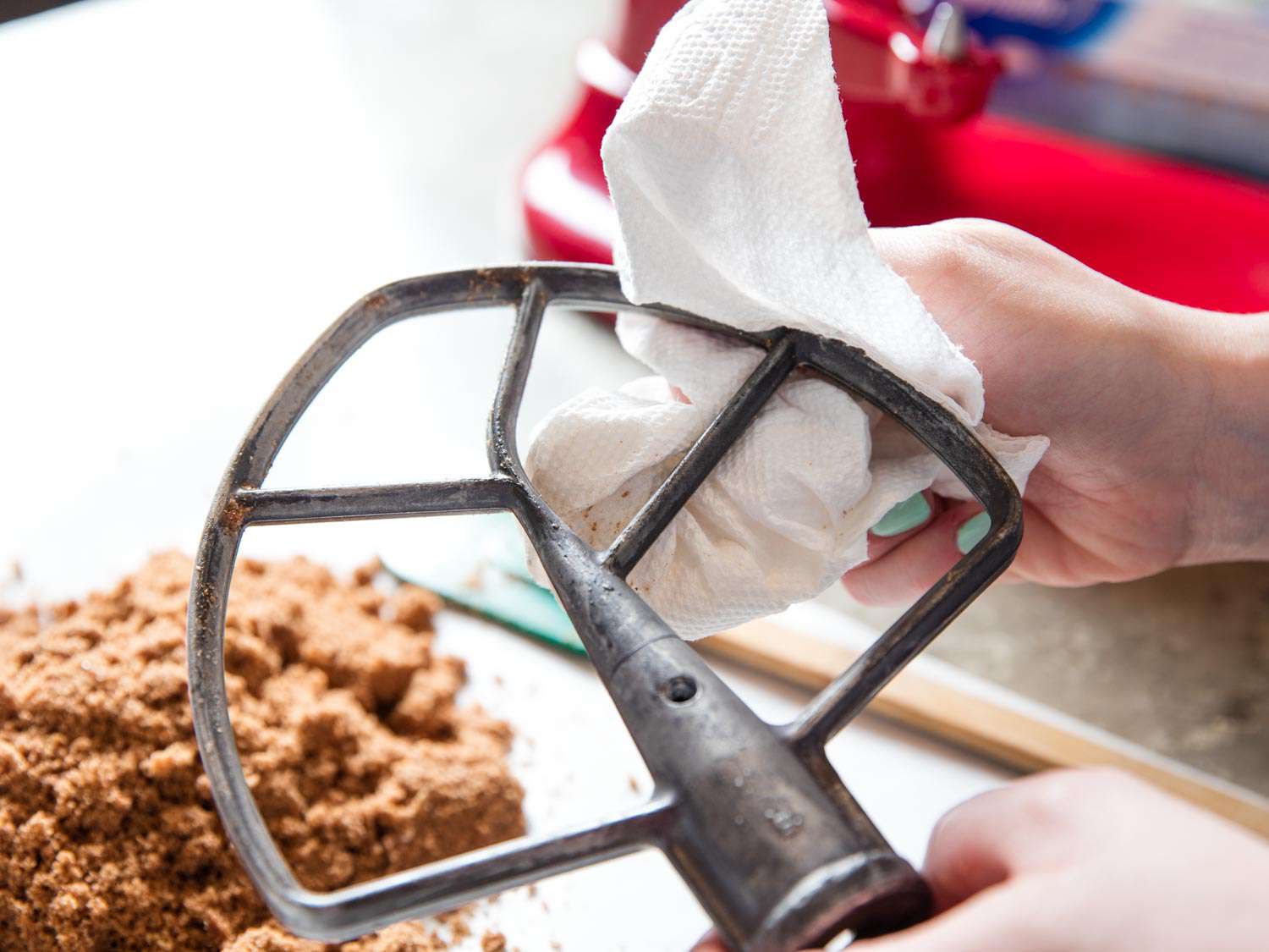 Wiping down a paddle attachment with paper towel.