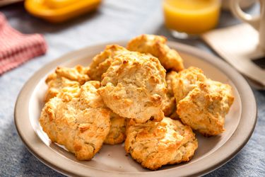 Several quick and easy drop biscuits on a plate with juice and butter in the background.