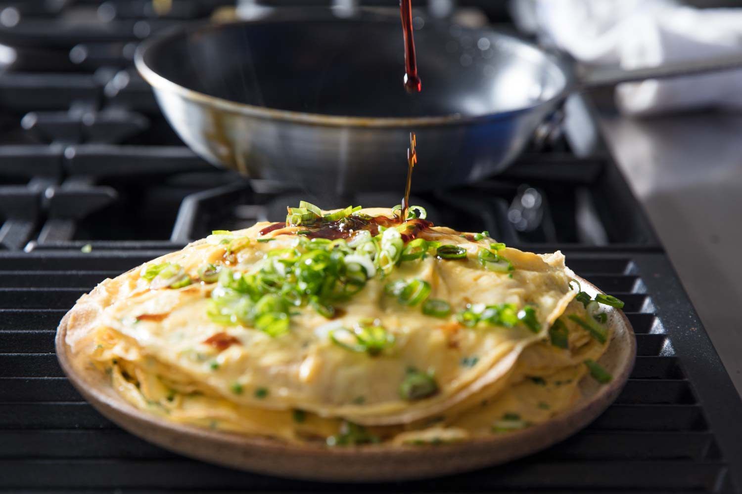 Soy sauce being drizzled over layered omelette.