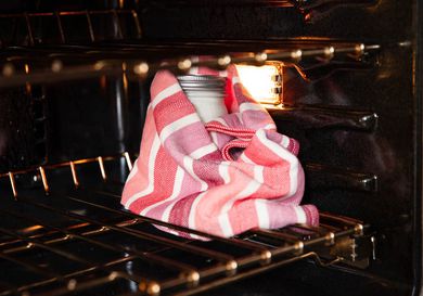 用毛巾把酸奶包好，把它放在开着灯的烤箱里，这样可以让它保持足够的温度。