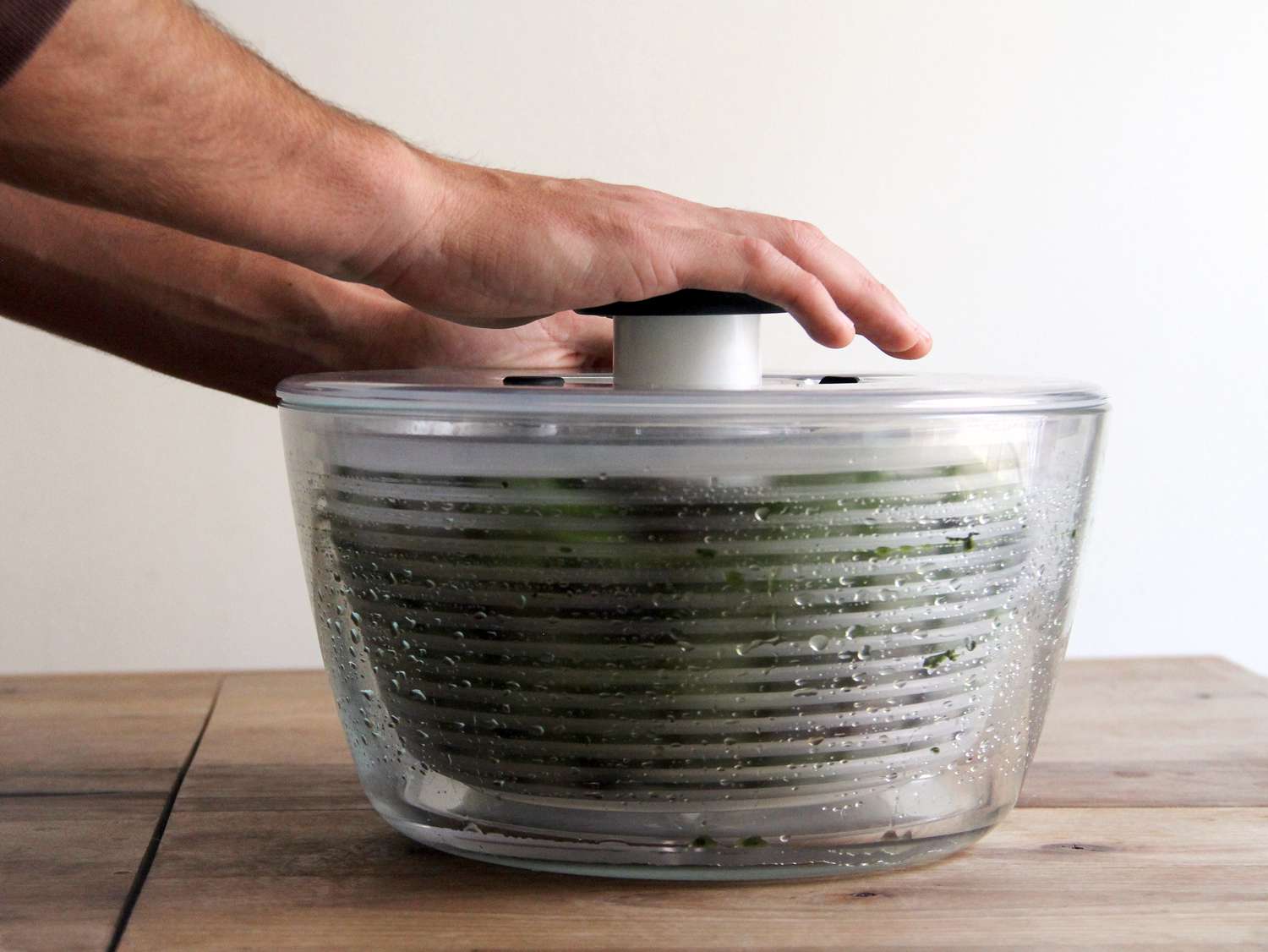 The OXO glass salad spinner spinning lettuce dry