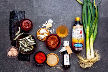 Overhead view of Korean pantry ingredients arranged on a dark gray surface.