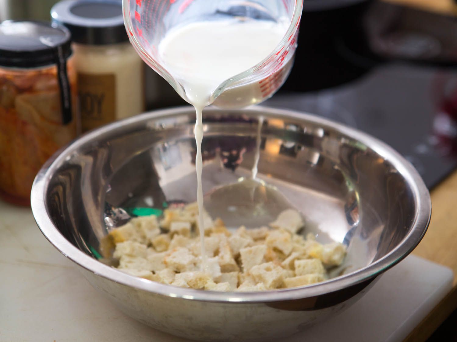 Pouring milk over bread cubes for making Swedish meatballs.