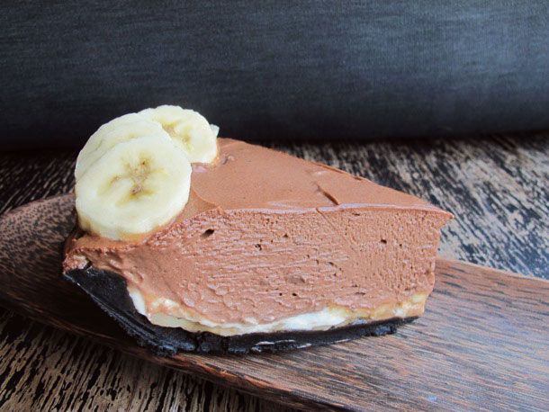 一块裹着巧克力皮的巧克力奶油派，上面放着香蕉片