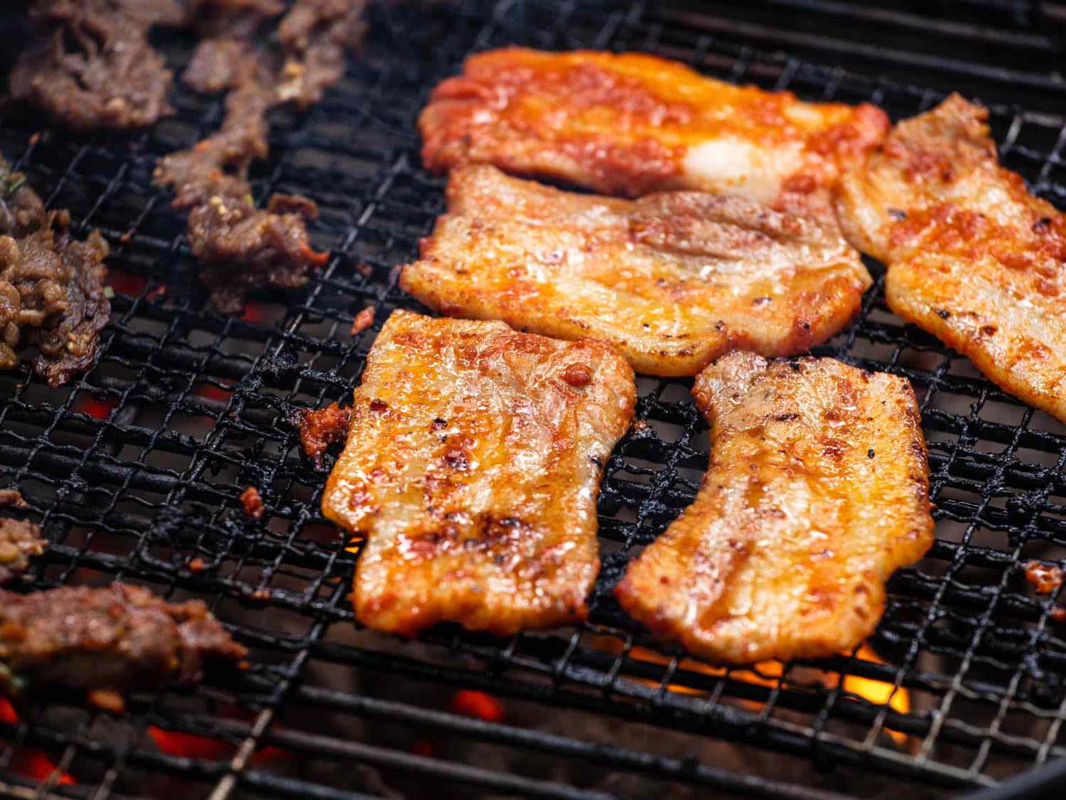 Closeup of pieces of pork belly on the grill.
