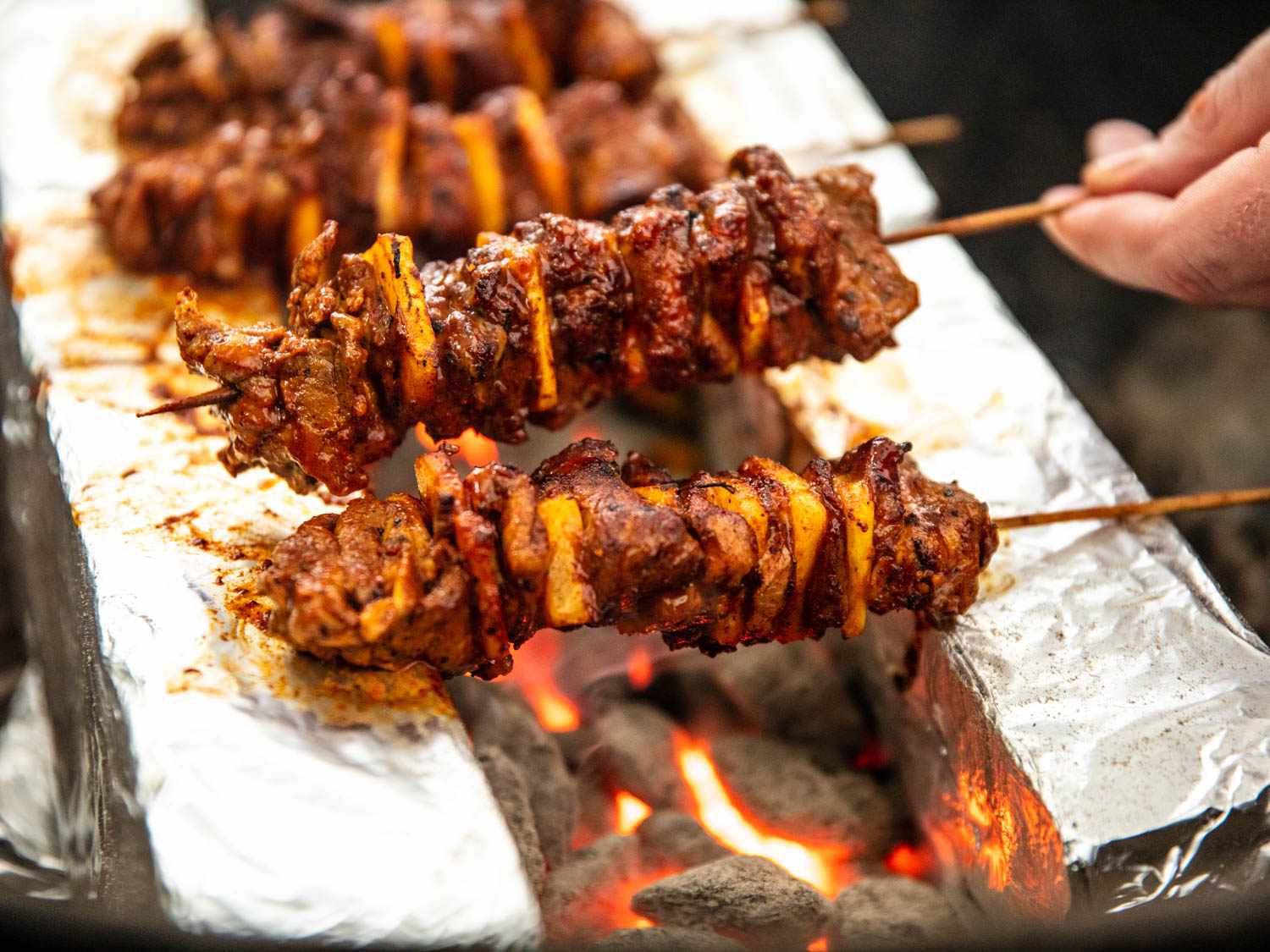 艾尔牧师串排列上面几英寸rench of hot coals, suspended between foil-wrapped bricks.