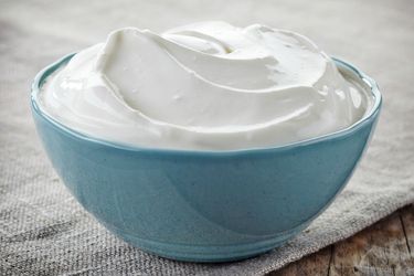 A small blue bowl full of sour cream.