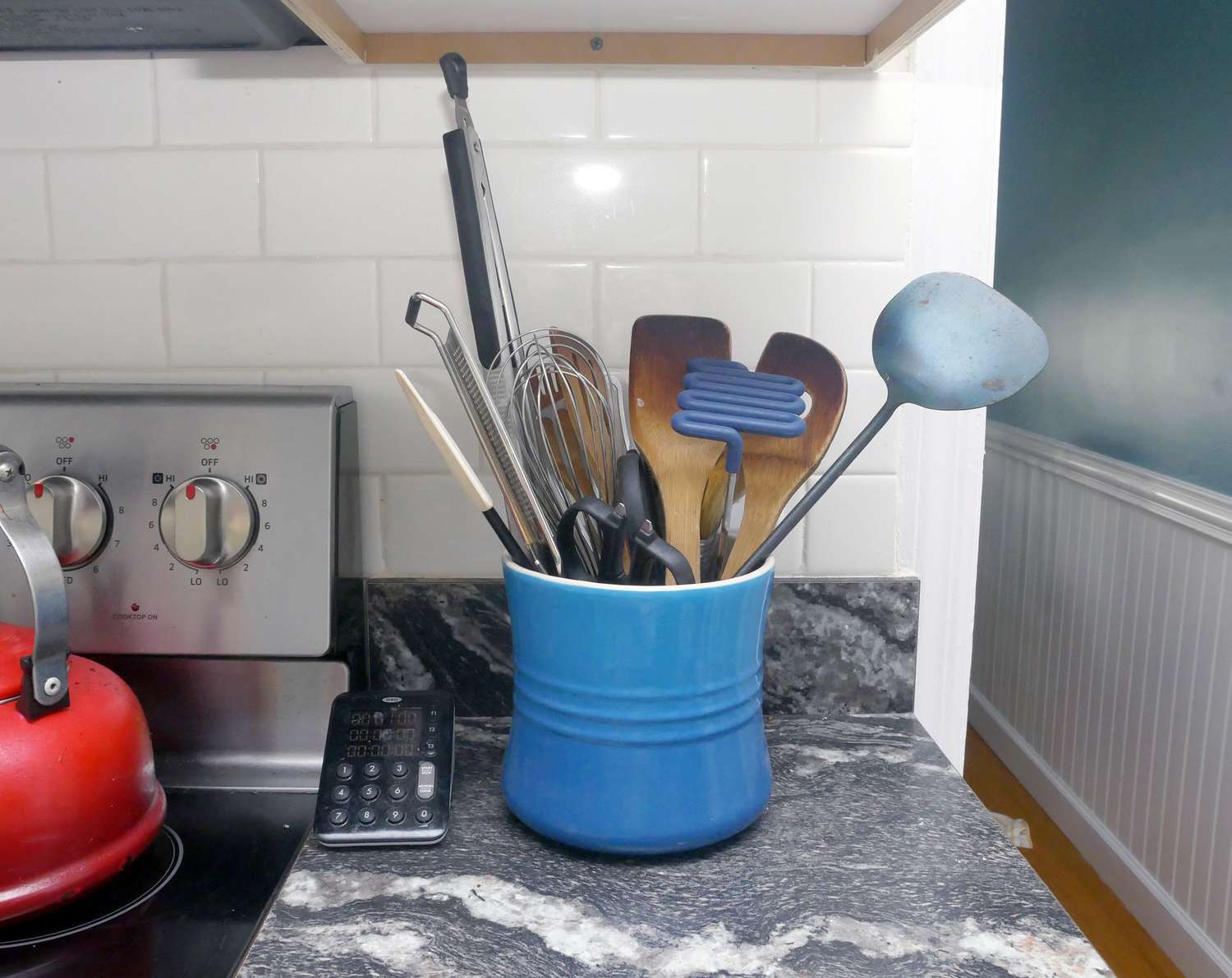 a blue crock utensil crock on a counter by a stove