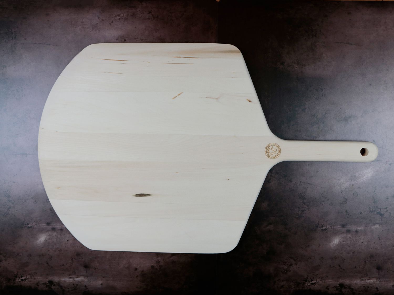 a wooden pizza peel on a dark background