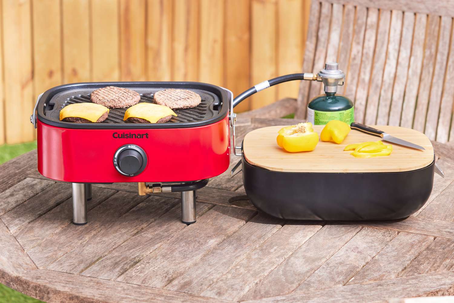 a portable gas grill on a wooden tabletop