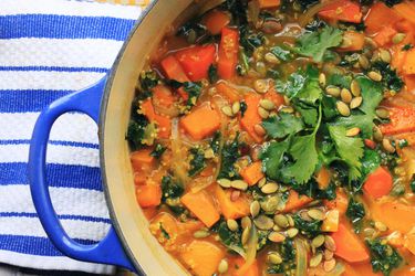 A blue Dutch oven filled with vegan butternut squash soup with kale.