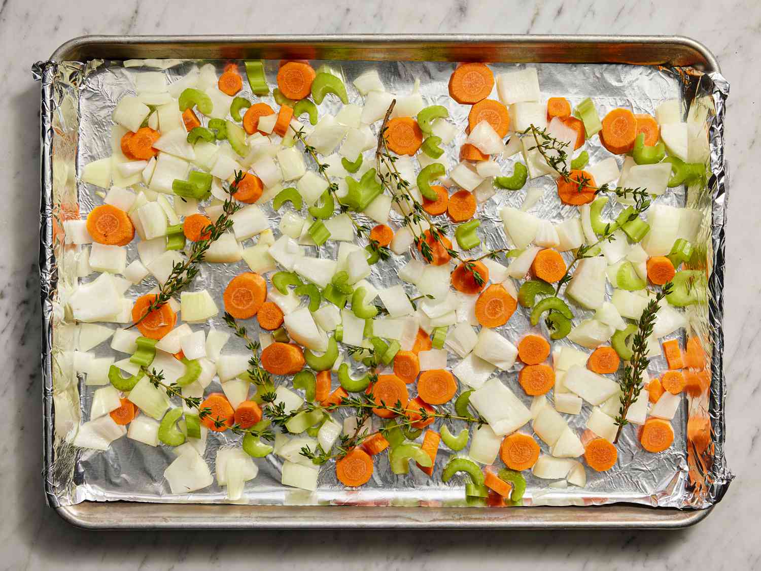 Vegetables and herbs scattered on a baking tray