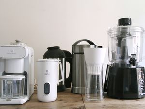 a variety of nut milk makers lined up on a wooden countertop