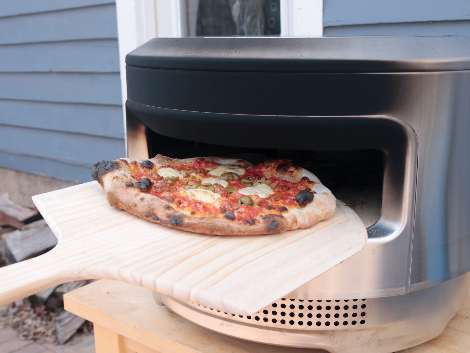 a pizza being rotated in an outdoor pizza oven
