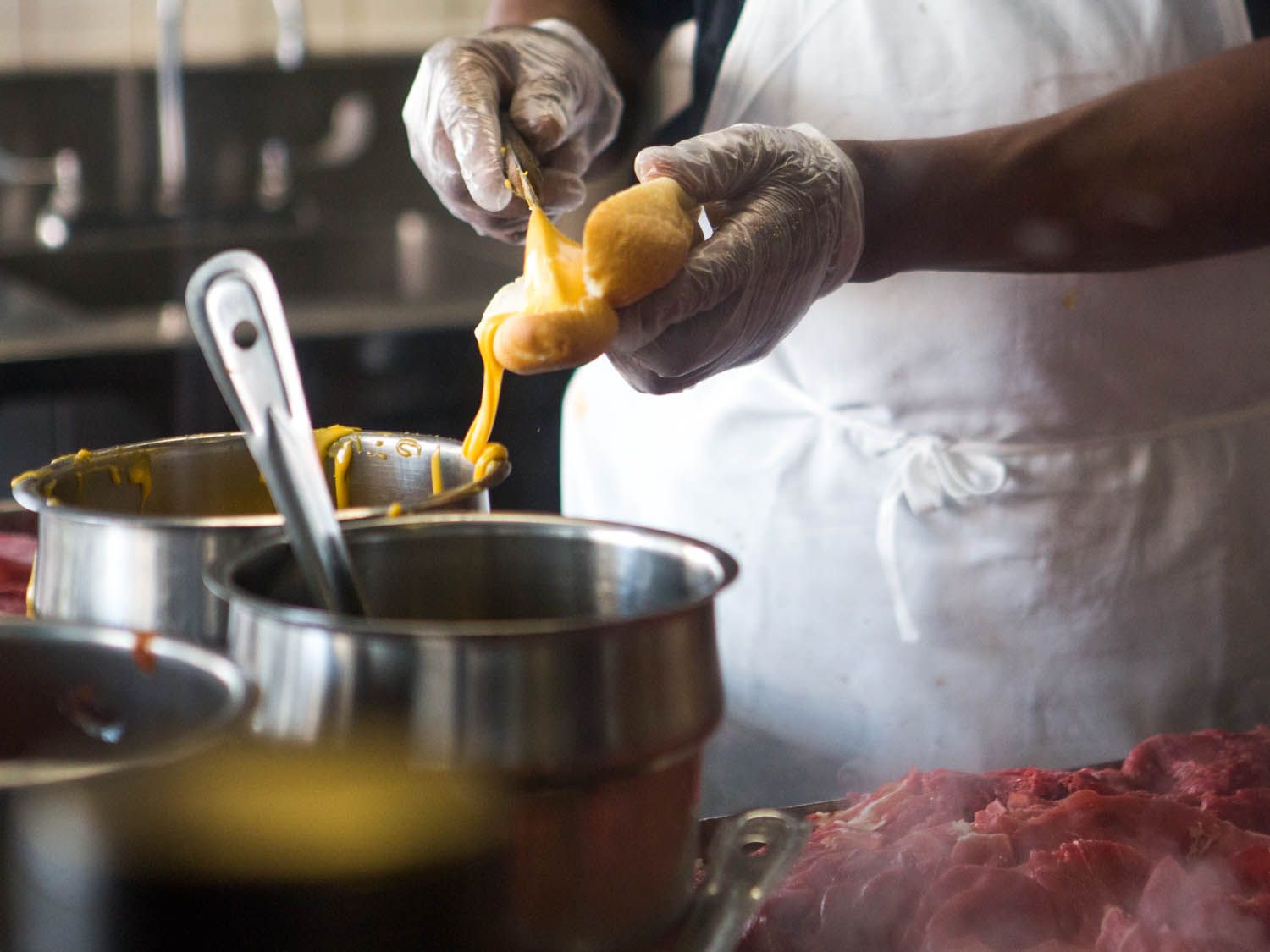 Cheez Whiz being slathered onto a Philly cheesesteak.