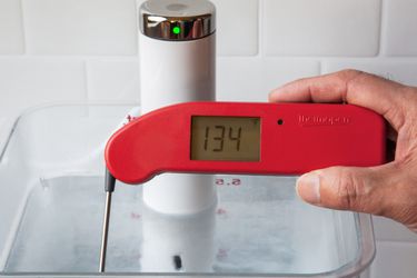 一个Thermapen one taking the temperature of a sous vide water bath set to 134 degrees