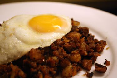 A plate of roast beef hash with a fried egg on top.