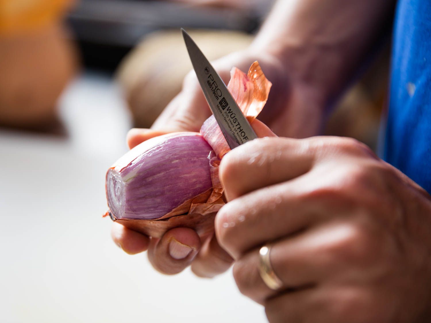 A pairing knife peeling a shallot