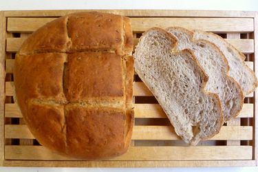 一大块自制面包放在木板上，旁边放着三片面包。