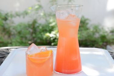glass and pitcher of tequila and campari with tangerine slice